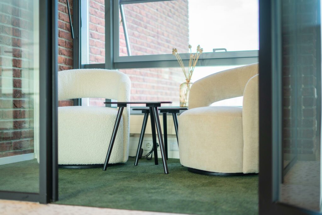 Twee moderne fauteuils met ronde vormen en een set zwarte bijzettafels in een zithoek aan de Joop Geesinkweg.